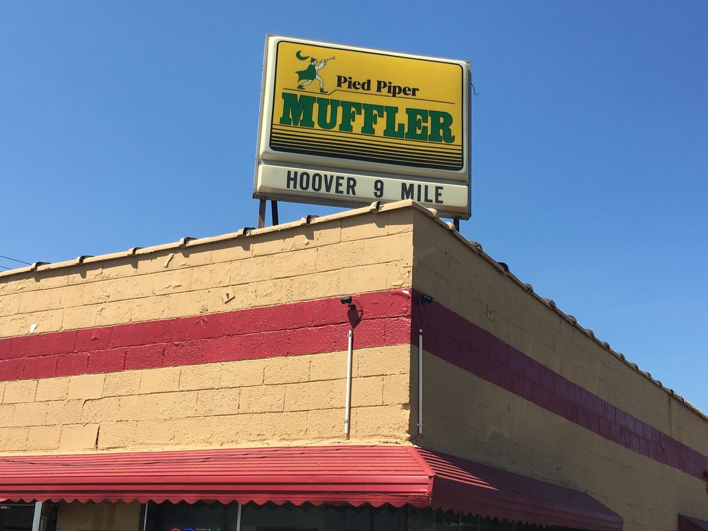 Rooftop sign above the shop reading Pied Piper Muffler, Hoover 9 Mile