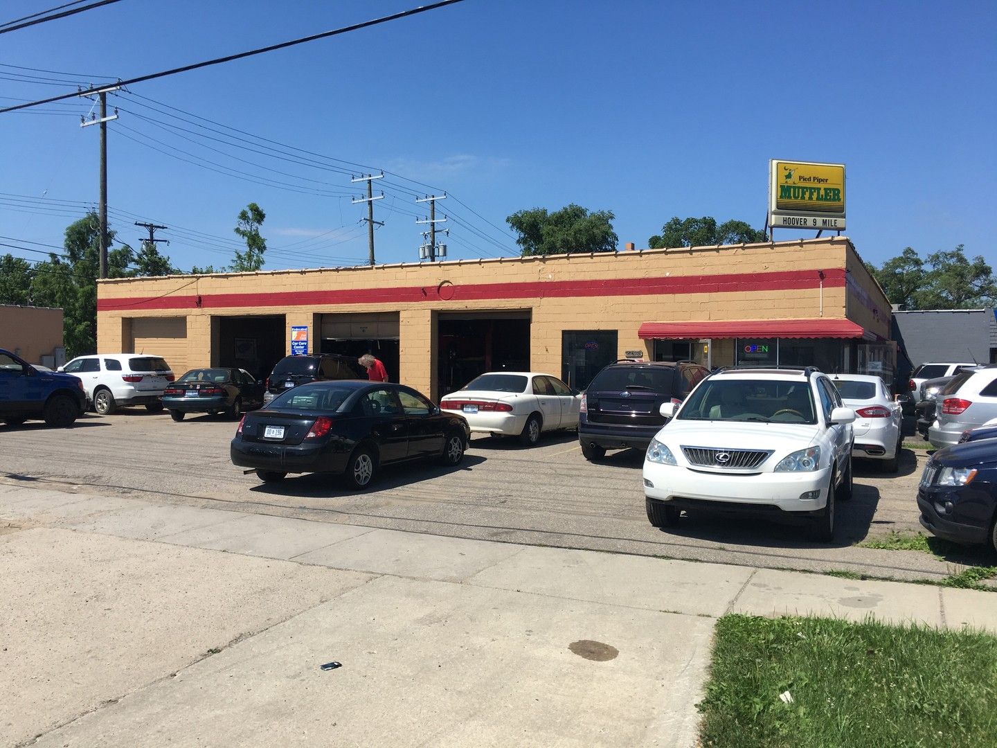 The Hoover & 9 Mile Auto Repair building on Hoover Road in Warren, with service bay doors open and vehicles parked out front